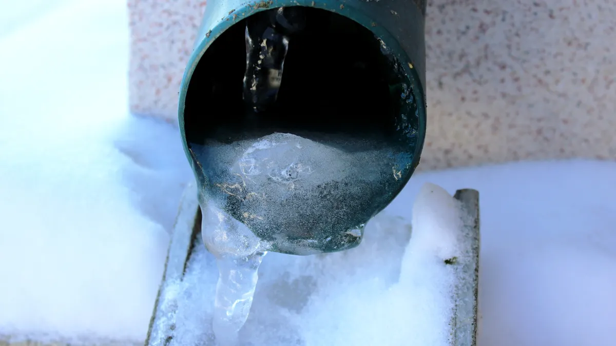 Frozen gutter downspout blocked by ice in Hartford winter